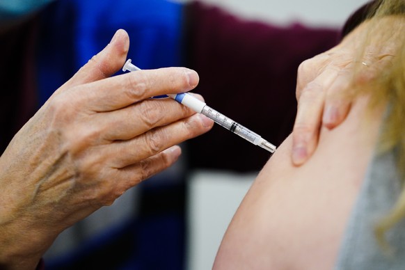 FILE - A health worker administers a dose of a COVID-19 vaccine during a vaccination clinic at the Keystone First Wellness Center in Chester, Pa., on Dec. 15, 2021. Government advisers are debating Tu ...