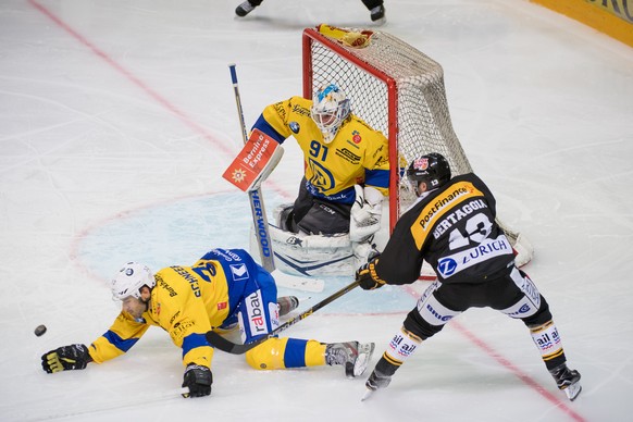 Davos&#039;s Noah Schneeberger and goalkeeper Gilles Senn, left, fight for the puck with Lugano&#039;s Alessio Bertaggia, right, during the preliminary round game of the National League A (NLA) Swiss  ...