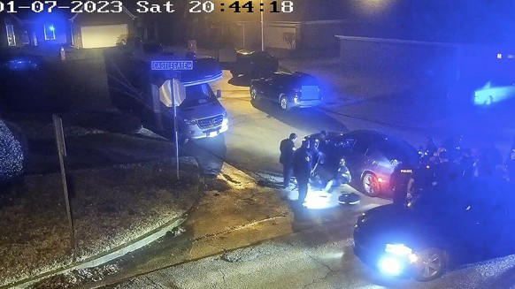 FILE - In this image from a video released by the City of Memphis, paramedics stand near Tire Nichols, sitting leaning against a car, while police officers, right, stand on the scene after a brutal assault...