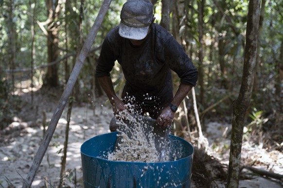 A gold miner washes a carpet used to trap gold fragments as he works at an illegal mine in the Amazon jungle, in the Itaituba area of Para state, Brazil, Friday, Aug. 21, 2020. It