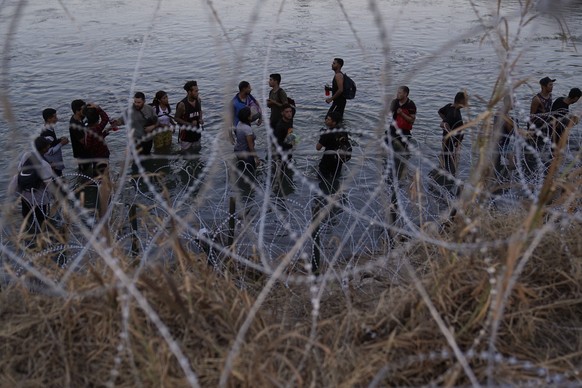 FILE - Migrants wait to climb over concertina wire after they crossed the Rio Grande and entered the U.S. from Mexico, Sept. 23, 2023, in Eagle Pass, Texas. A divided Supreme Court on Tuesday, March 1 ...