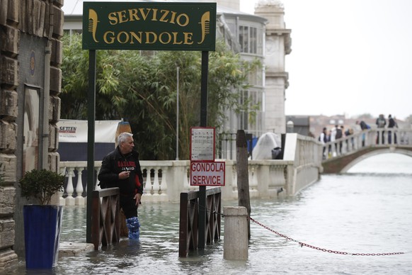 A man stands next to a gondola service in flooded Venice, Italy, Sunday, Nov. 17, 2019. Venetians are bracing for the prospect of another exceptional tide in a season that is setting new records. Offi ...