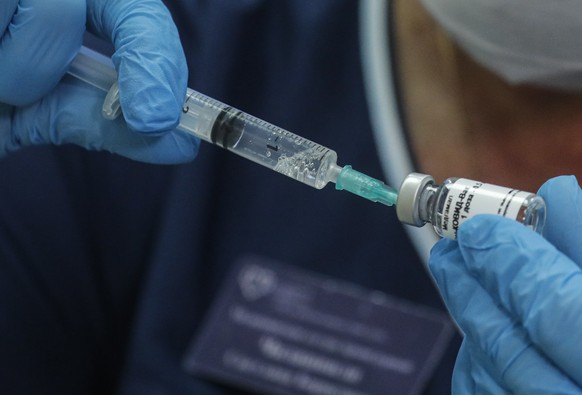 epa08675837 A Russian medical worker prepares a trial vaccine against COVID-19 for a volunteer in a post-registration phase of the test at outpatient hospital number 68 in Moscow, Russia, 17 September ...