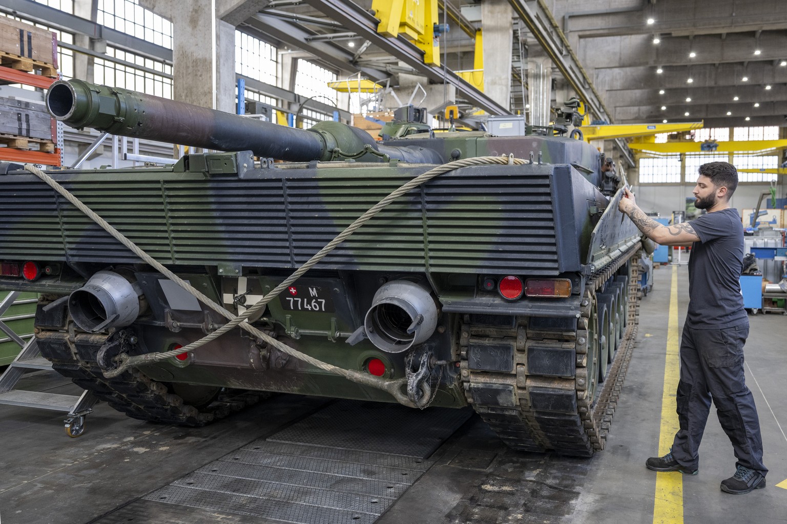 Ein Mechaniker wartet die Raupen an einem Panzer vom Typ Leopard 2 in einer Wartungshalle der RUAG, am Montag, 20. Maerz 2023, in Thun. (KEYSTONE/Peter Schneider)