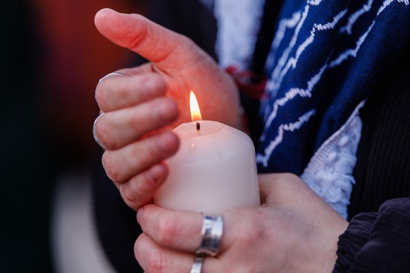 epa12642904 A person holds a burning candle during a vigil in front of the US embassy for Renee Nicole Good, who was shot during an ICE operation in South Minneapolis, in Berlin, Germany, 11 January 2 ...