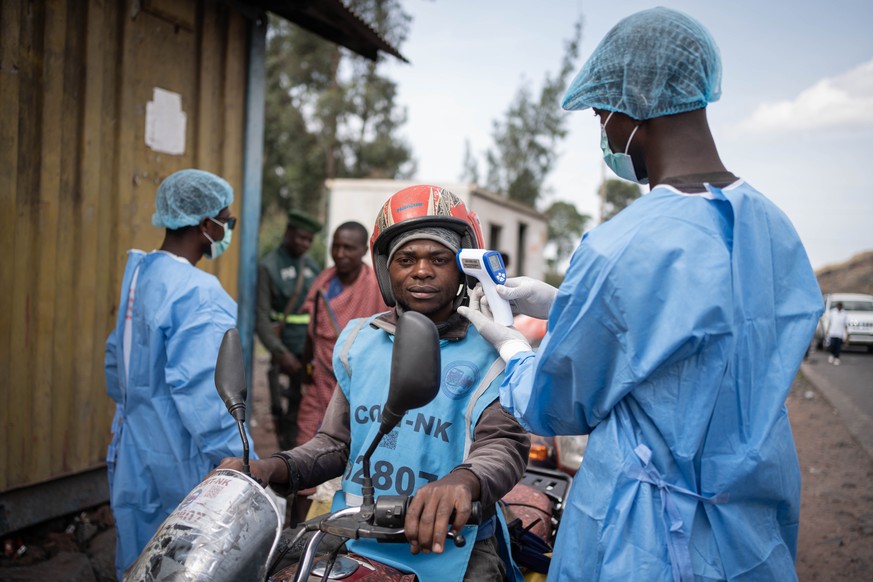 KEYPIX - epa12997409 Health workers in protective gowns and masks check locals' temperature as a preventive measure against Ebola in Kanyaruchinya, near Goma, North Kivu, Democratic Republic of C ...