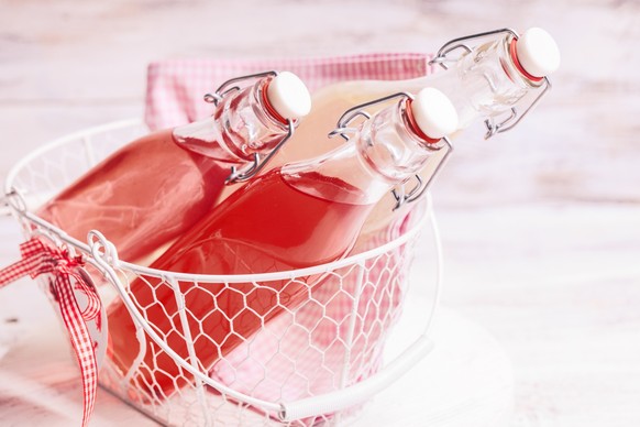 Berry lemonade in the bottles in basket on the grass