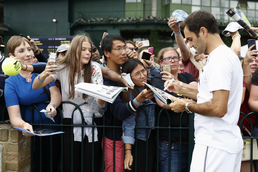 Roger Federer of Switzerland poses with fans and signs autographs after a training session at the All England Lawn Tennis Championships in Wimbledon, London, Monday, July 3, 2017. (KEYSTONE/Peter Klau ...