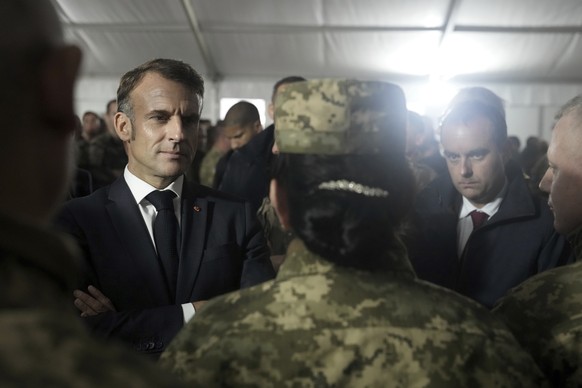 French President Emmanuel Macron, left, and French Defense Minister Sebastien Lecornu, right, speak with Ukrainian soldiers in a military camp in eastern France, Wednesday, Oct. 9, 2024 as he meets fo ...