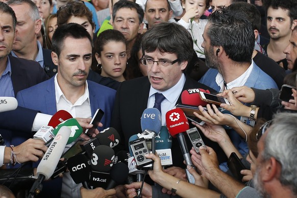 Catalan President Carles Puigdemont, centre, speaks to the media at a sports center, assigned to be a polling station by the Catalan government and where Puigdemont was originally expected to vote, in ...