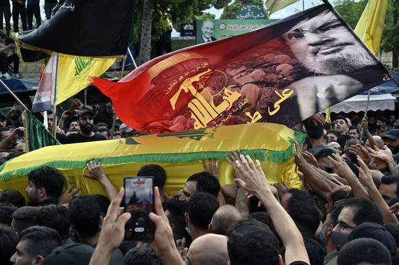 epa11619381 Mourners carry the coffin of commander of Hezbollah Ibrahim Akil, who died in an Israeli strike on 20 September, during the funeral procession in Beirut, Lebanon, 22 September 2024. At lea ...
