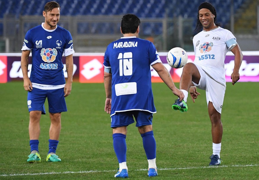 epa05582830 Argentinian soccer legend Diego Armando Maradona (C) with Italian forward and captain of AS Roma Francesco Totti (L) and Brazilian forward Ronaldinho (R) perform prior the &#039;Match of P ...