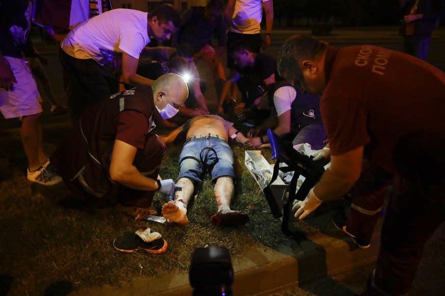 Paramedics treat a wounded person after clashes with police man in Minsk, Belarus, Sunday, Aug. 9, 2020. Police and protesters clashed in Belarus' capital and the major city of Brest on Sunday after t ...