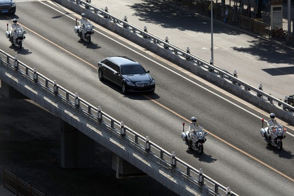Police motorcycles escort a stretch limousine with a golden emblem similar to one North Korean leader Kim Jong Un has used previously, along a road closed to other traffic in Beijing, China, Tuesday,  ...