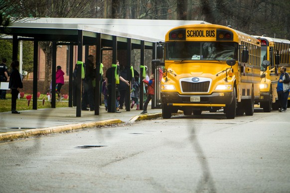 FILE - Students exit a school bus during the first day back to Richneck Elementary School on January 30, 2023, in Newport News, Virginia.  A grand jury in Virginia has indicted the mother of a 6-year-old boy who…