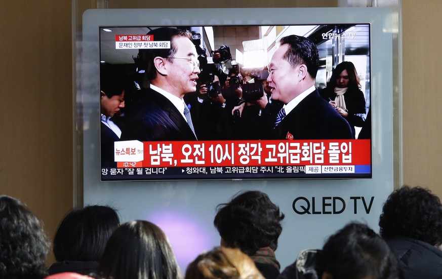 People watch a TV screen showing South Korean Unification Minister Cho Myoung-gyon, left, meets with the head of North Korean delegation Ri Son Gwon before talks, at Seoul Railway Station in Seoul, So ...