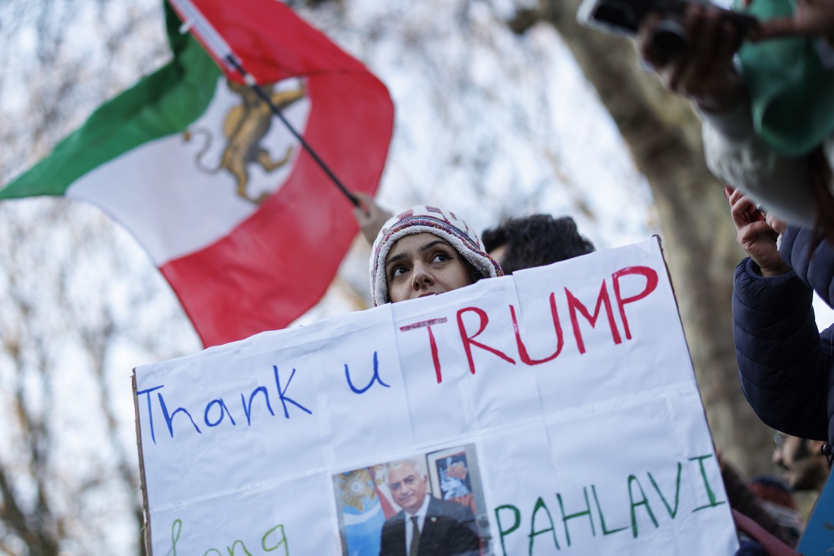 epa12623485 Demonstrators and supporters of exiled Crown Prince of Iran, Reza Pahlavi, hold placards and wave a historic Iranian national flag during a protest against the Iranian regime outside the E ...