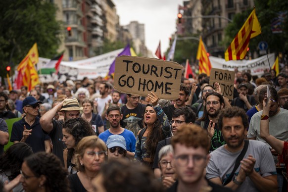 Demonstrators march shouting slogans against the Formula 1 Barcelona Fan Festival in downtown Barcelona, Spain, Wednesday, June 19, 2024. Around 500 Barcelona residents protest against mass tourism du ...