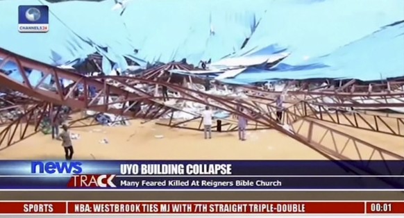 In this image taken from video people stand at the scene after the roof of The Reigners Bible Church International collapsed onto worshippers in Uyo, southern Nigeria on Saturday, Dec. 10, 2016, killi ...