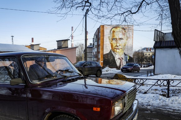 epaselect epa10401675 A man drives a VAZ-2107 Zhiguli (LADA 2107) past a large mural depicting Russian President Vladimir Putin, on the side of a five-story residential building in Kashira, Moscow reg ...