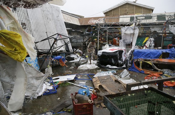 Residents walk along destroyed stalls at a public market due to strong winds as Typhoon Mangkhut barreled across Tuguegrao city in Cagayan province, northeastern Philippines on Saturday, Sept. 15, 201 ...