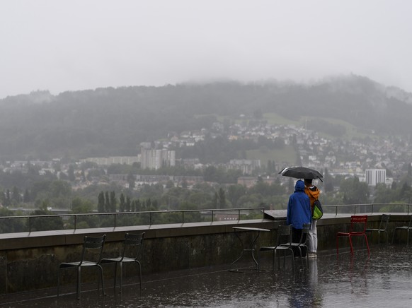 Personen mit einem Regenschirm schauen sich die Aussicht unter Regen an, am Samstag, 7. August 2021, in Bern (KEYSTONE/Anthony Anex)