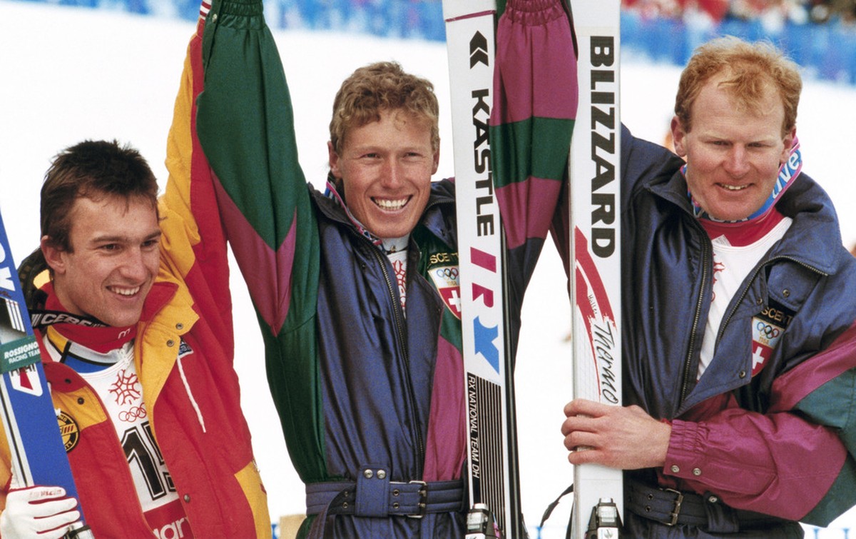 Die Schweizer Pirmin Zurbriggen, Mitte, Gold, Peter Mueller, rechts, Silber, und der Franzose Franck Piccard, links, Bronze, freuen sich im Ziel ueber ihren Erfolg in der Ski alpin Abfahrt der olympis ...