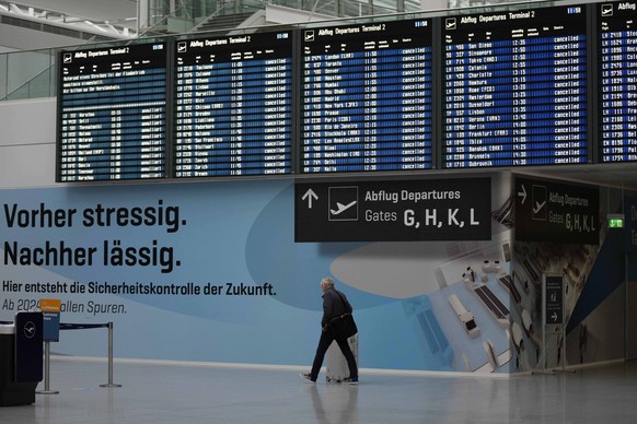 A man passes the deserted departure terminal during a strike in Bavaria at the airport in Munich, Germany, Sunday, March 26, 2023. An increased number of travelers in Germany boarded trains and planes ...