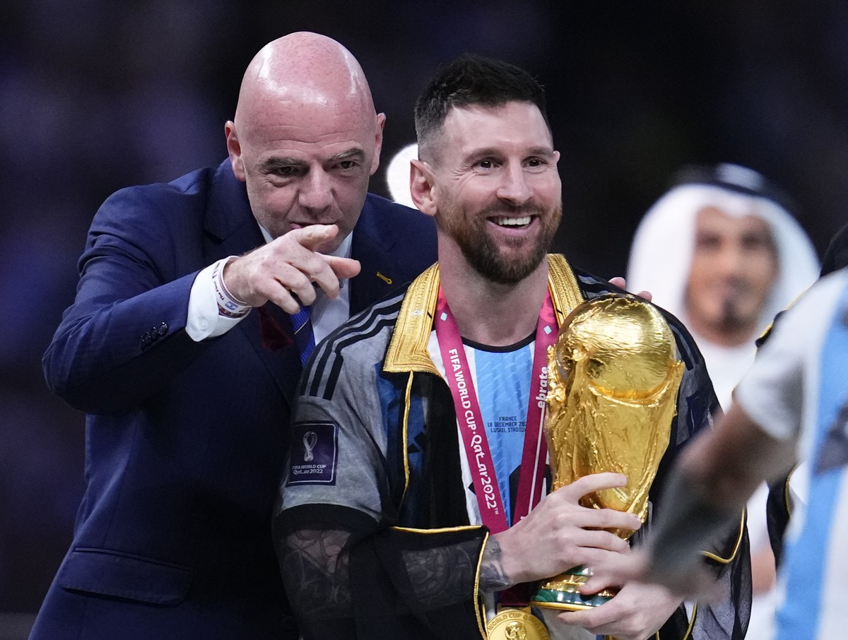 Argentina's Lionel Messi walks towards his teammates after receiving from FIFA President Gianni Infantino the trophy after Argentina defeated France in the World Cup final soccer match at the Lus ...