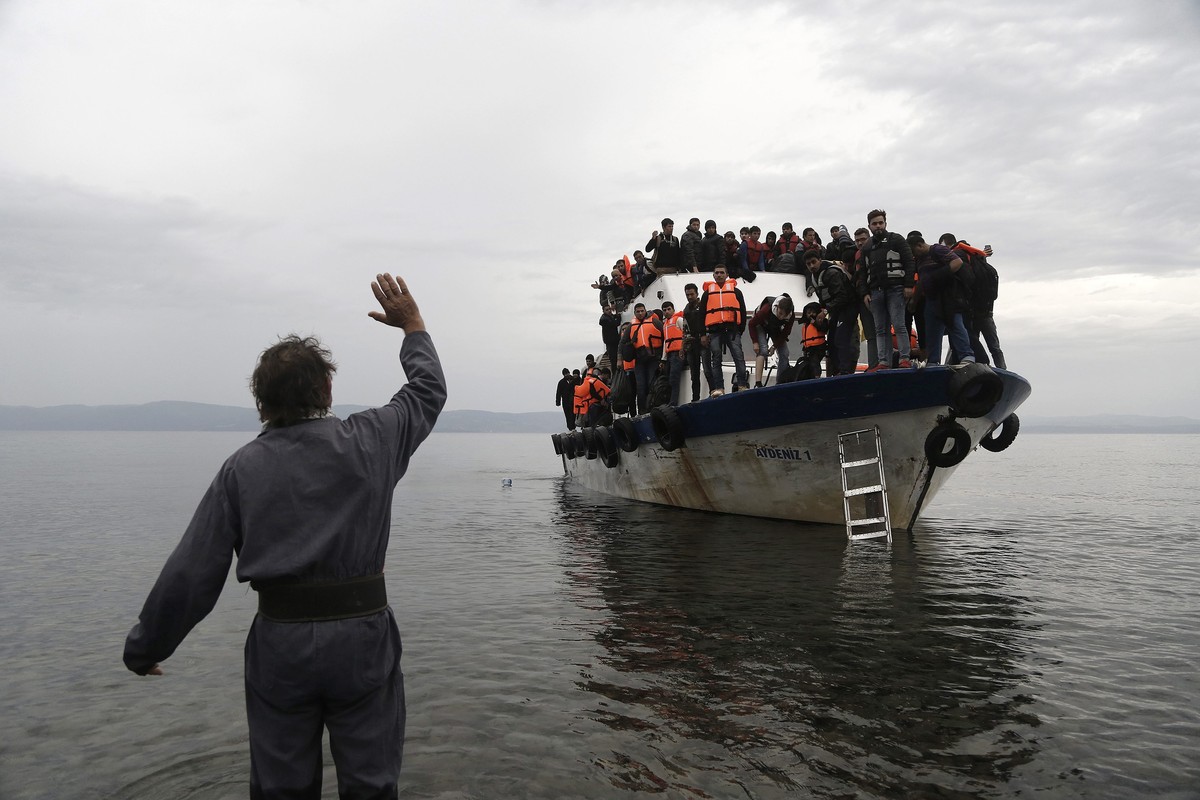 epaselect epa04973076 A resident waves to an overcrowded fishing boat carrying refugees and migrants after they crossed the Aegean sea from Turkey, Greece, 11 October 2015. A recently agreed European  ...