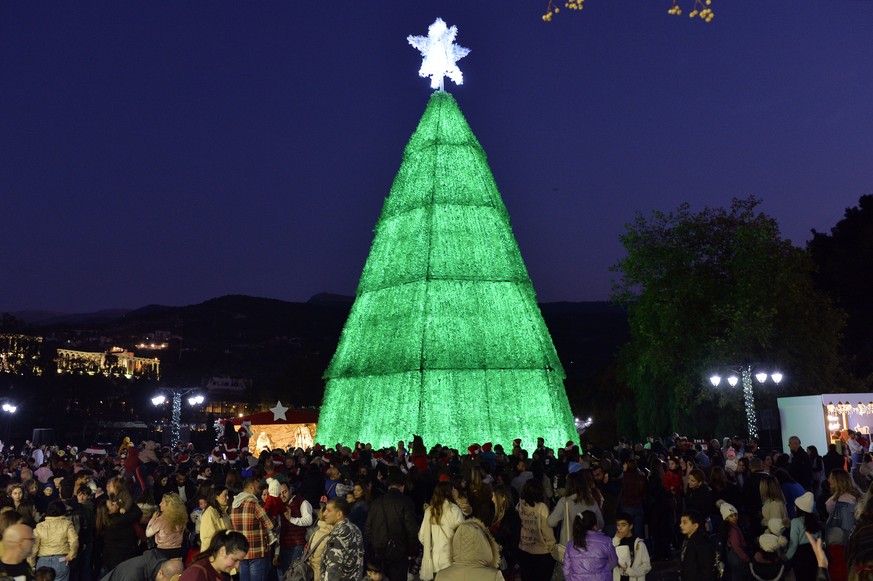 epa10360360 A 18-meter-high Christmas tree made of discarded plastic bottles at the entrance of Bnachii Lake, Zgharta district, northern Lebanon, 10 December 2022. The Christmas tree with a diameter o ...