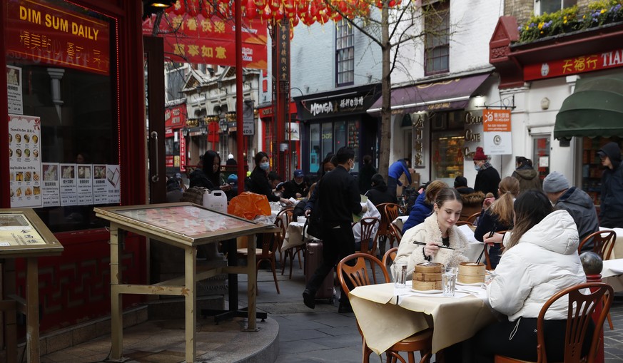 Customers eat outside a Chinese restaurant in the Soho area of London, Monday, April 12, 2021, as restaurants, bars and pubs can open and serve people who can be seated outside. Millions of people in  ...