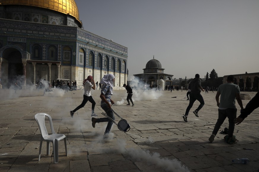 Palestinians run away from tear gas during clashes with Israeli security forces at the Al Aqsa Mosque compound in Jerusalem&#039;s Old City Monday, May 10, 2021. Israeli police clashed with Palestinia ...