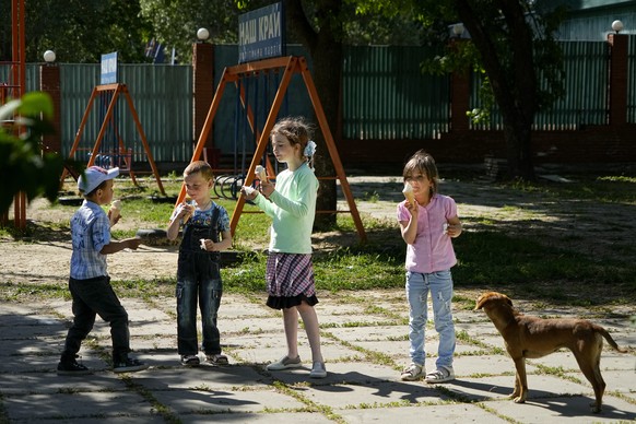 Children eat ice-cream at a park in Kherson, Kherson region, south Ukraine, Friday, May 20, 2022. The Kherson region has been under control of the Russian forces since the early days of the Russian mi ...