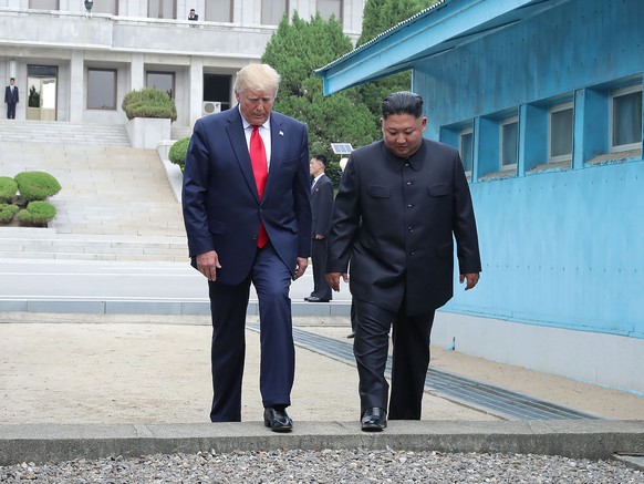 In this Sunday, June 30, 2019, photo provided by the North Korean government, North Korean leader Kim Jong Un, right, and U.S. President Donald Trump cross the border line at the border village of Pan ...