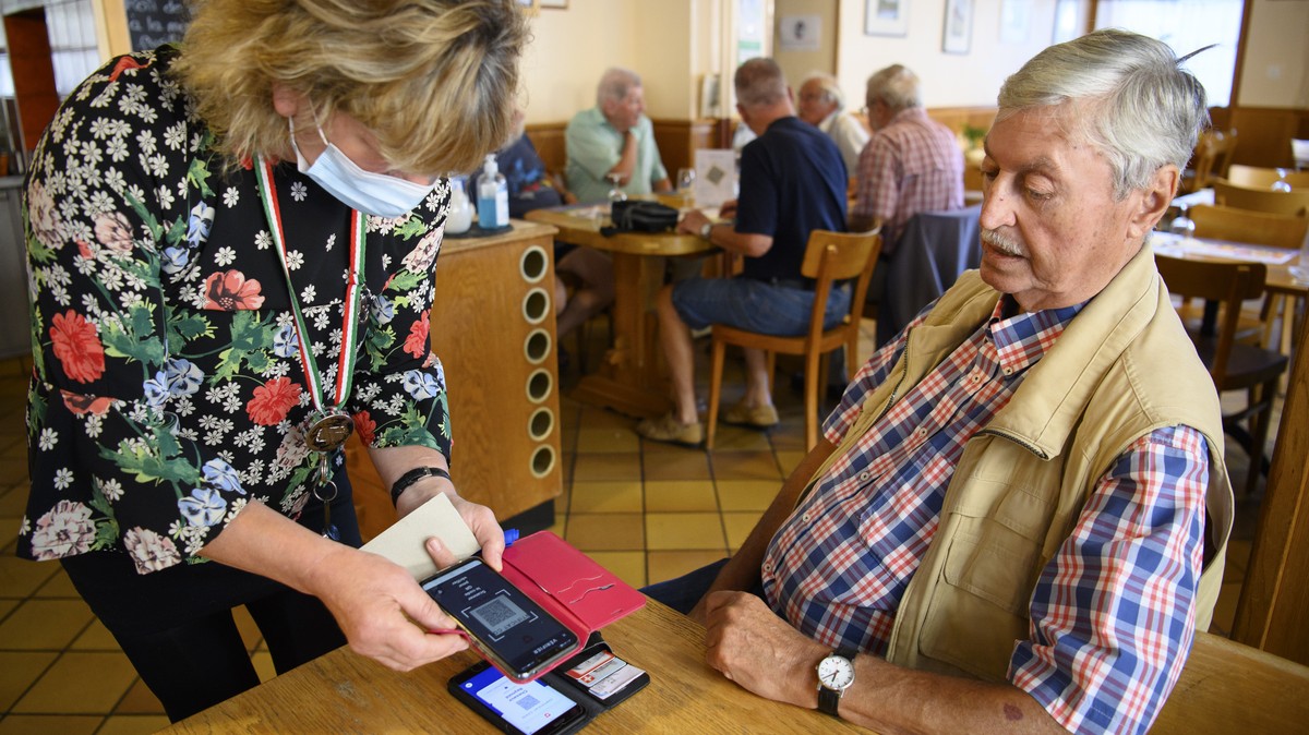 Une serveuse verifie un certificat COVID d'un client a l'aide d'un smartphone et l'application Certificat Covid Check dans le cafe restaurant de L'Europe ce lundi 13 septembre ...