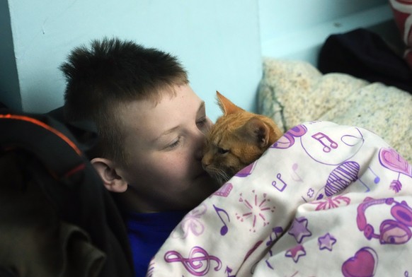 A boy and his cat hide from the Russian artillery shelling in a school basement in the village of Horenka close to Kyiv, Ukraine, Sunday, March 6, 2022. On Day 11 of Russia's war on Ukraine, Russian troops shelled encircled cities, and it appeared that a second attempt to evacuate civilians from the besieged port city of Mariupol had failed due to continued violence.(AP Photo/Efrem Lukatsky)