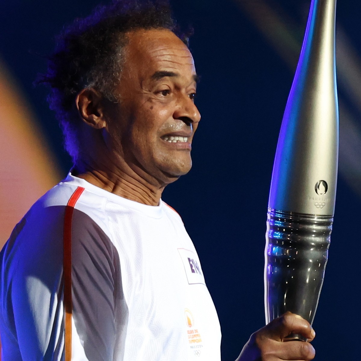epa11479046 Former Tennis player, Yannick Noah holds the torch in the last relay of the day at tthe townhall of Paris, France, 14 July 2024. The Olympic torch relay arrived in Paris on Bastille Day, t ...