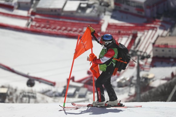 A course worker removes a flag from a gate on the men&#039;s downhill course after race was postponed due to high winds at the 2022 Winter Olympics, Sunday, Feb. 6, 2022, in the Yanqing district of Be ...