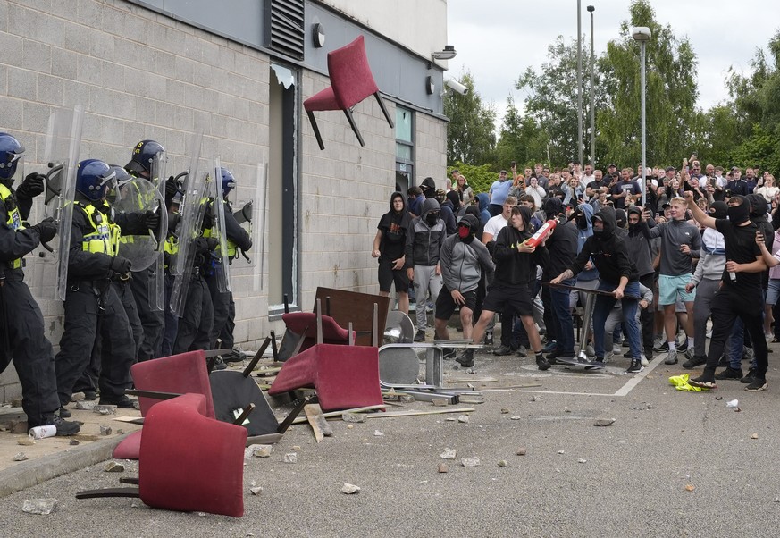 A chair is thrown at police officers as trouble flares during an anti-immigration protest outside the Holiday Inn Express in Rotherham, England, Sunday Aug. 4, 2024. (Danny Lawson/PA via AP)