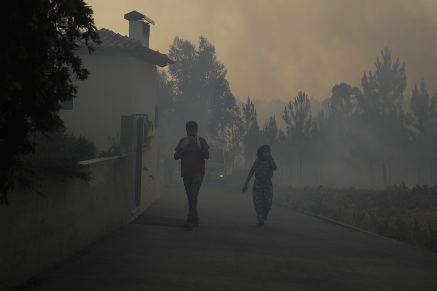 epa10064287 Locals walk in thick smoke during a fire in Cruzinha, Alvaiazere, Portugal, 10 July 2022. The fire that has been burning in forest stands since 07 July in Cumeada, Ourem, remains active an ...