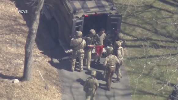 This image made from video provided by WCVB-TV, shows Jack Teixeira, in T-shirt and shorts, being taken into custody by armed tactical agents on Thursday, April 13, 2023, in Dighton, Mass. (WCVB-TV vi ...