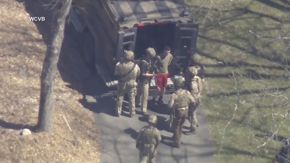 This image, taken from video from WCVB-TV, shows Jack Teixeira, wearing a T-shirt and shorts, being taken into custody by tactical officers in Dighton, Massachusetts, on Thursday, April 13, 2023.  (WCVB-TV vi...