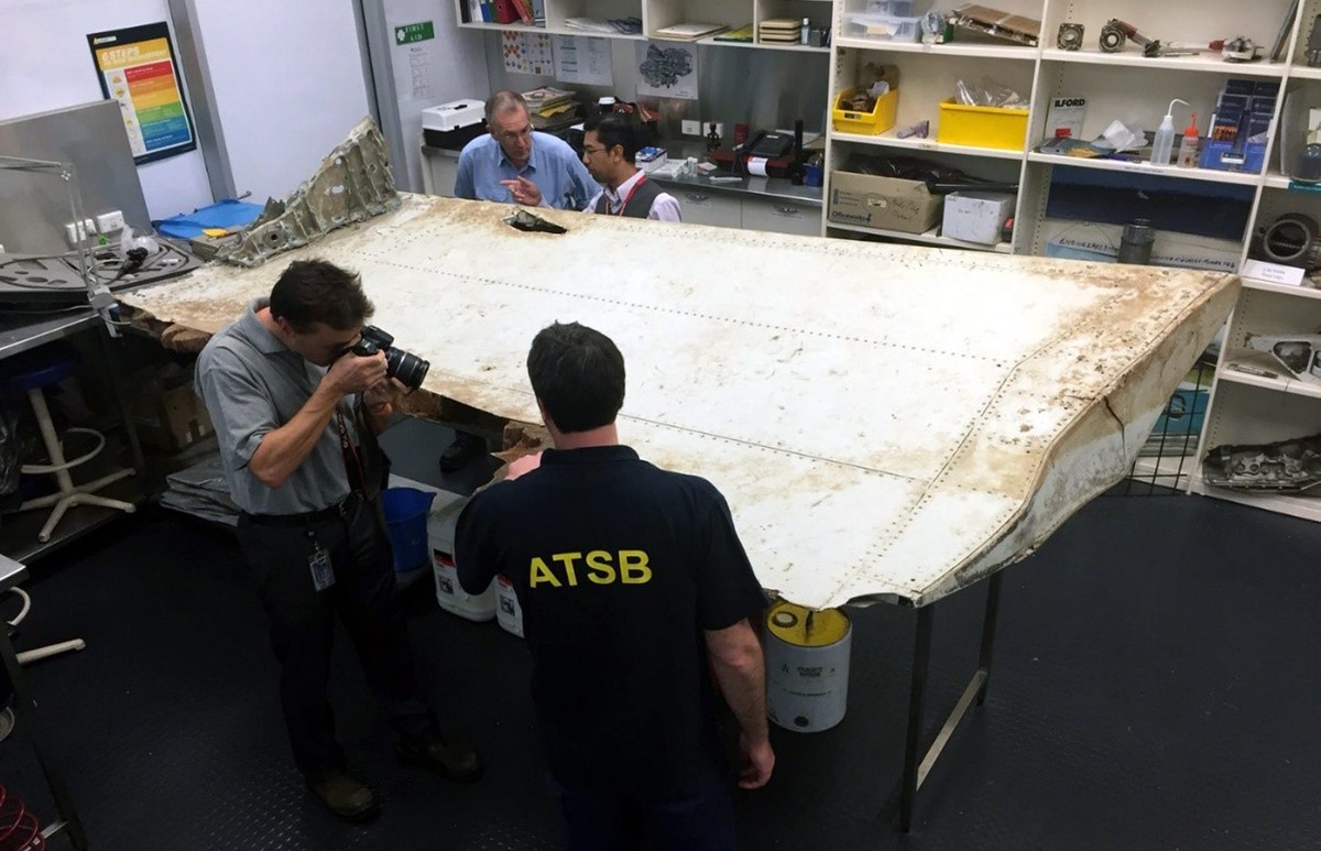 epa05432921 An undated handout picture made available by the Australian Transport Safety Bureau (ATSB) on 20 July 2016 shows Malaysian and Australian investigators examining a piece of aircraft debris ...