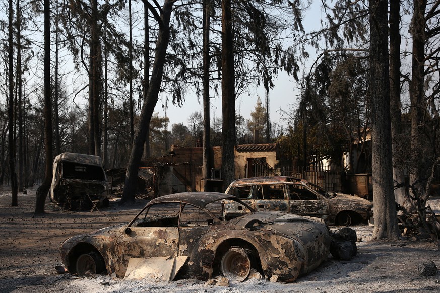 epa09393745 Burnt cars are seen after a wildfire in the area of Varybobi, northeastern suburb of Athens, Greece, 04 August 2021. The major fire that broke out in the wildland-urban interface in Varybo ...