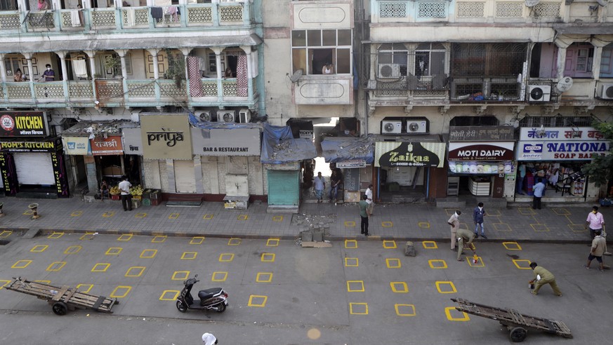Civic workers mark positions for maintaining physical distance at market place in Mumbai, India, Friday, March 27, 2020. Some of India's legions of poor and others suddenly thrown out of work by ...