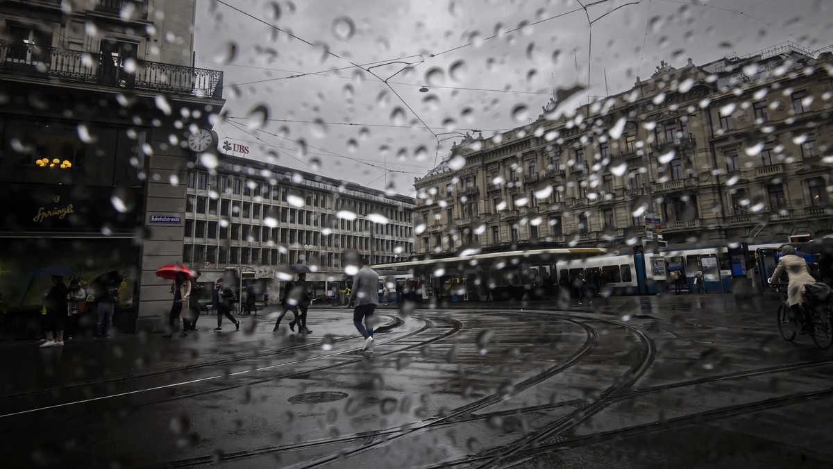 People walk past the headquarters of the Swiss bank Credit Suisse, right, and UBS, left, at the Paradeplatz .in Zurich, Switzerland, on Friday, March 24, 2023. (KEYSTONE/Michael Buholzer).