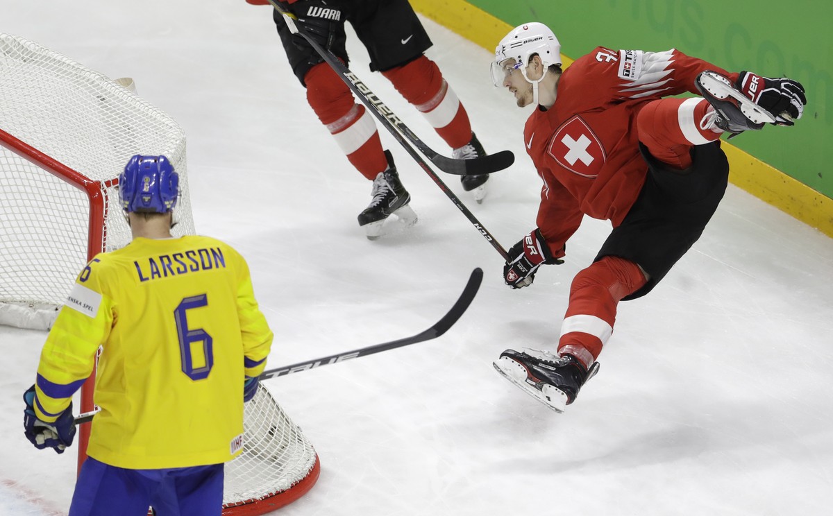 Switzerland's Dean Kukan, right, falls during the Ice Hockey World Championships final match between Sweden and Switzerland at the Royal arena in Copenhagen, Denmark, Sunday, May 20, 2018. (AP Ph ...