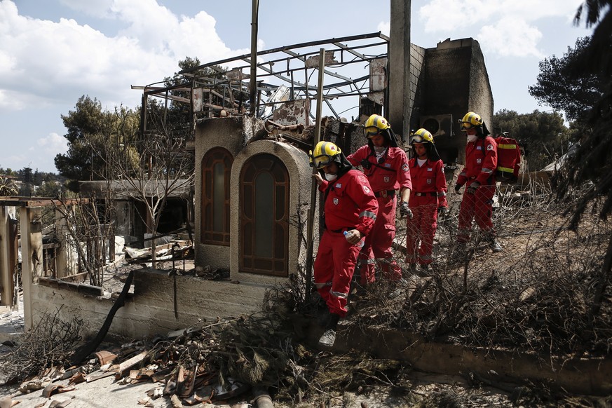 epa06909479 Members of the Greek Red Cross search for missing people at a burned house, following a deadly forest fire in Mati a northeast suburb of Athens, Greece, 25 July 2018. The death toll from f ...
