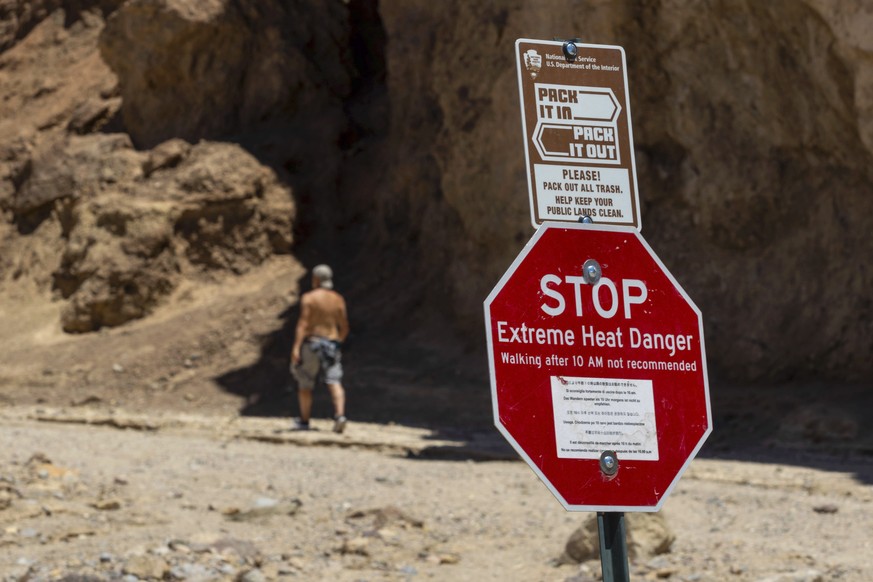 A hiker passes a sign warning hikers of extreme heat at the start of the Golden Canyon trail on July 11, 2023, in Death Valley National Park, Calif. A 71-year-old Los Angeles-area man died at the trai ...